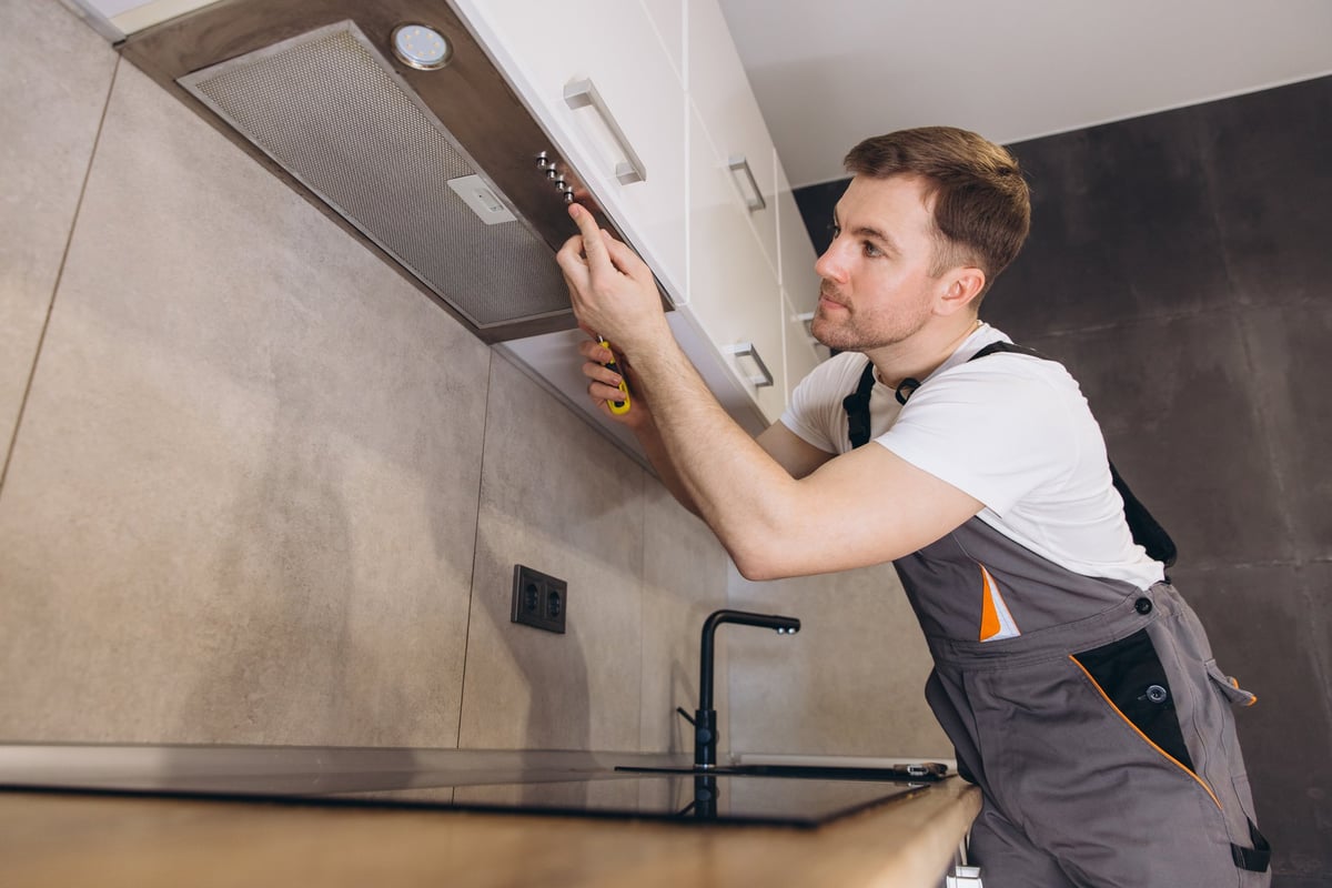 Plumber working in a modern kitchen, tightening screws during installation or repair service