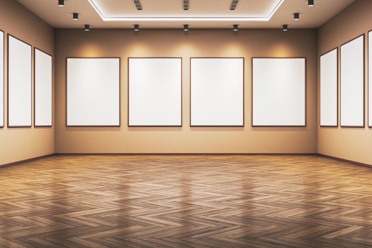 Blank poster frames on gallery walls with spotlights, wooden parquet floor, clean beige interior background