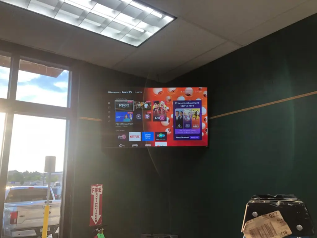 Commercial TV mounted on a green accent wall in an office break area