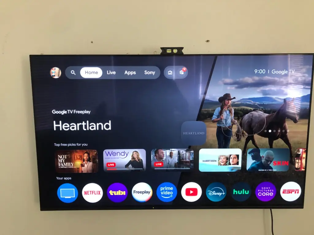 Wall mounted Google TV showing the streaming home screen after setup
