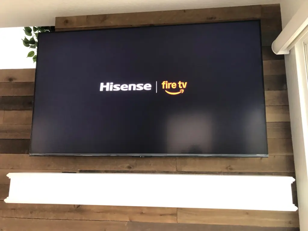Hisense Fire TV mounted on a reclaimed wood plank accent wall above a white mantel