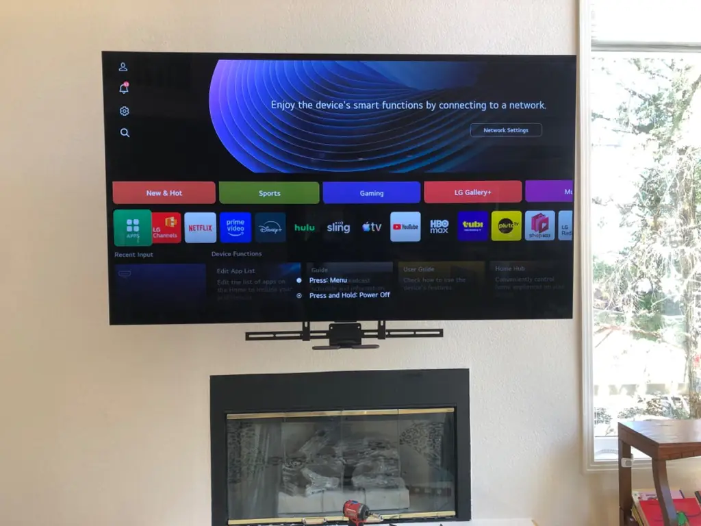 LG smart TV with soundbar mounted above a fireplace in a sunny living room