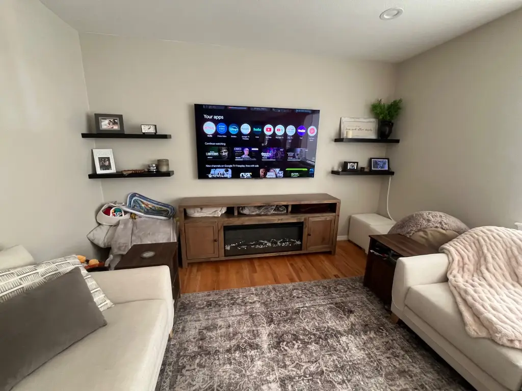 Living room TV mounted between floating shelves above a media console, installed by Dom's TV Mounting