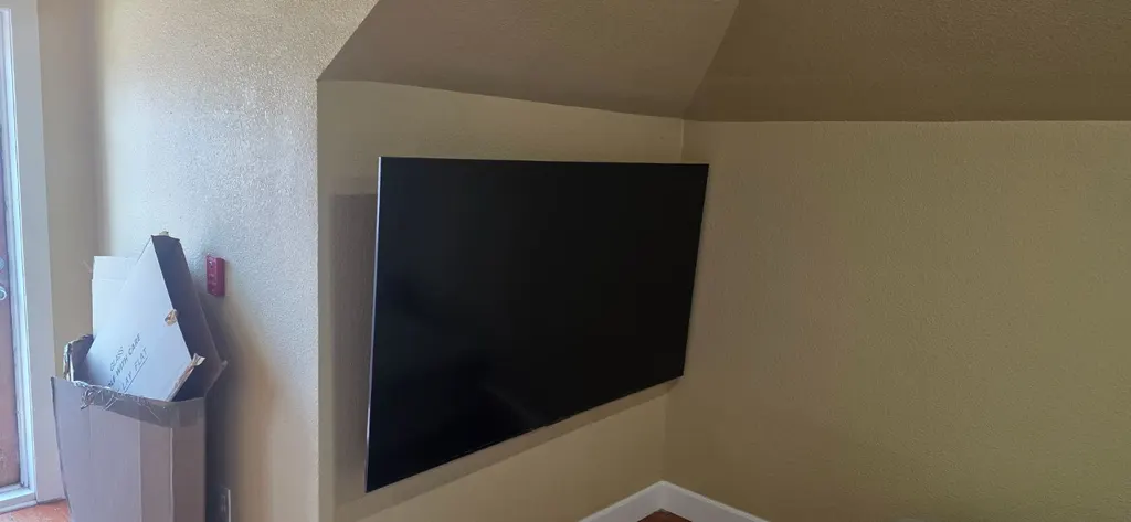 TV mounted in the corner of a room under a sloped ceiling