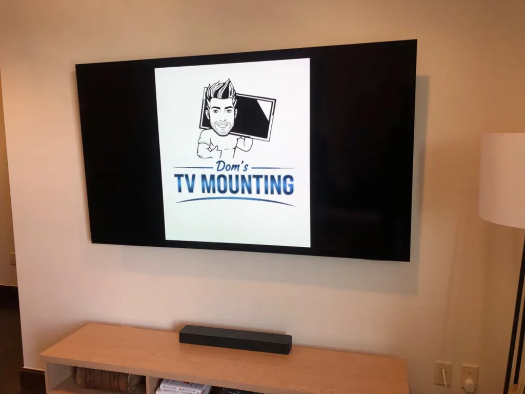 Large TV mounted level on a living room wall above a low console
