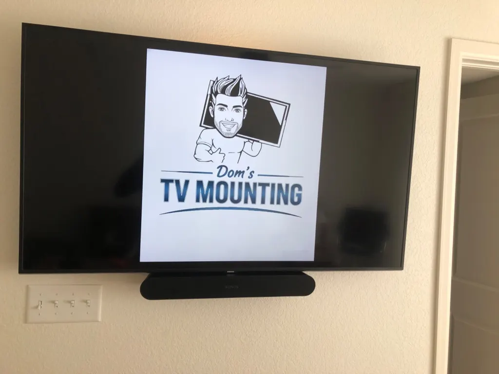 Flat TV mounted on a wall with a soundbar, installed by Dom's TV Mounting