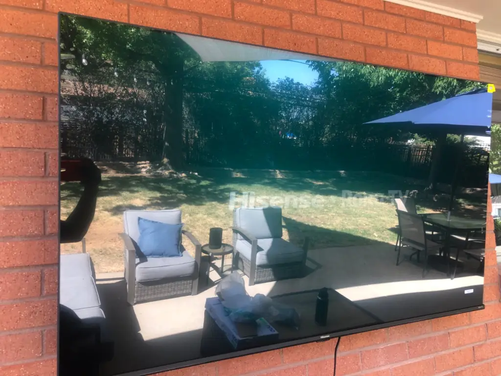 Outdoor TV mounted on a red brick exterior wall overlooking a backyard patio in Denver