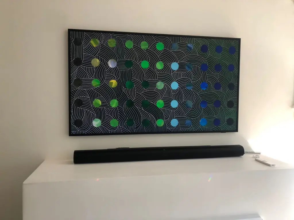 Samsung Frame TV in art mode showing green and blue dot artwork, mounted flush above a soundbar on a white wall in a Denver home