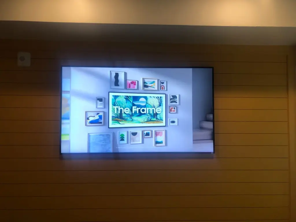 Samsung Frame TV displaying the words The Frame on a horizontal wood plank wall