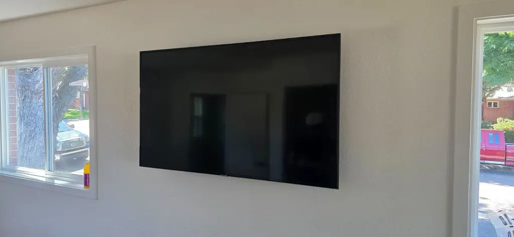 TV flush mounted on a smooth wall between a window and a door in an older home