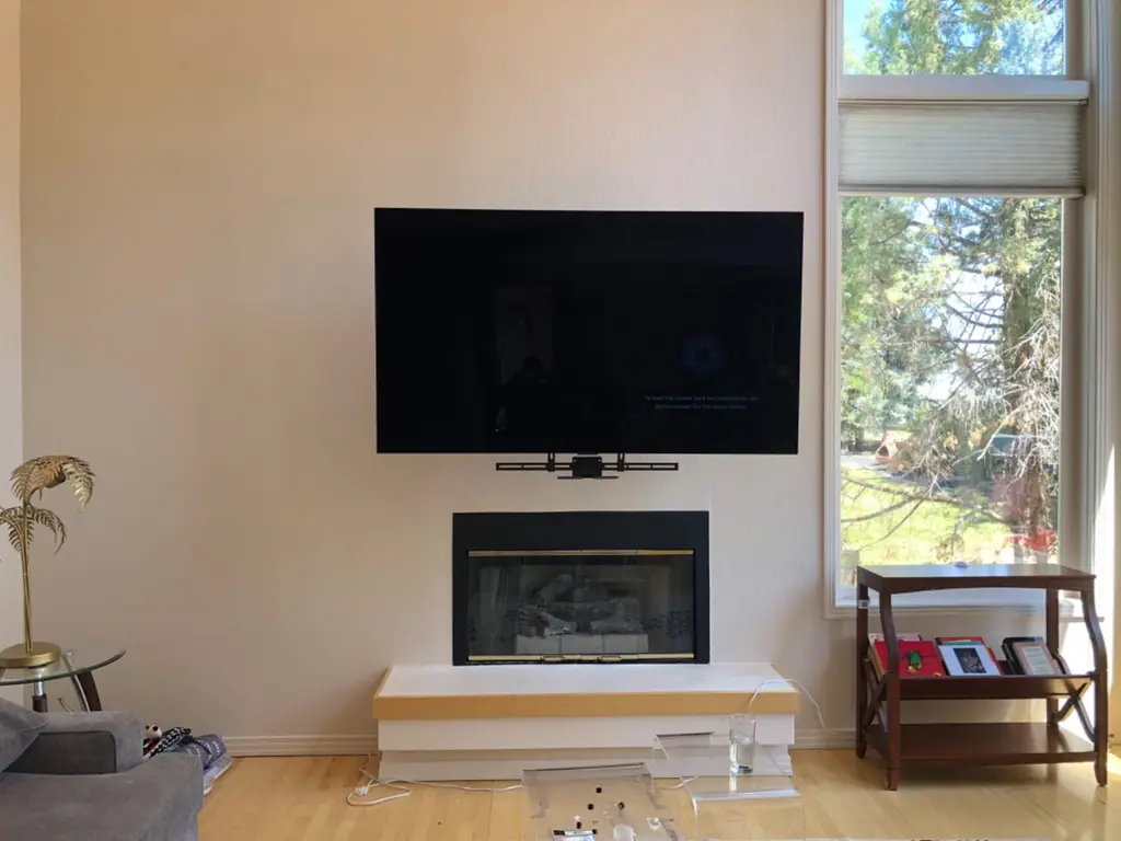 TV mounted above a gas fireplace next to a tall window with a streaming box mounted underneath
