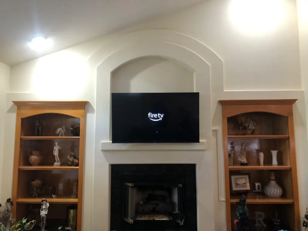TV mounted in an arched niche above a fireplace between built-in wood bookshelves