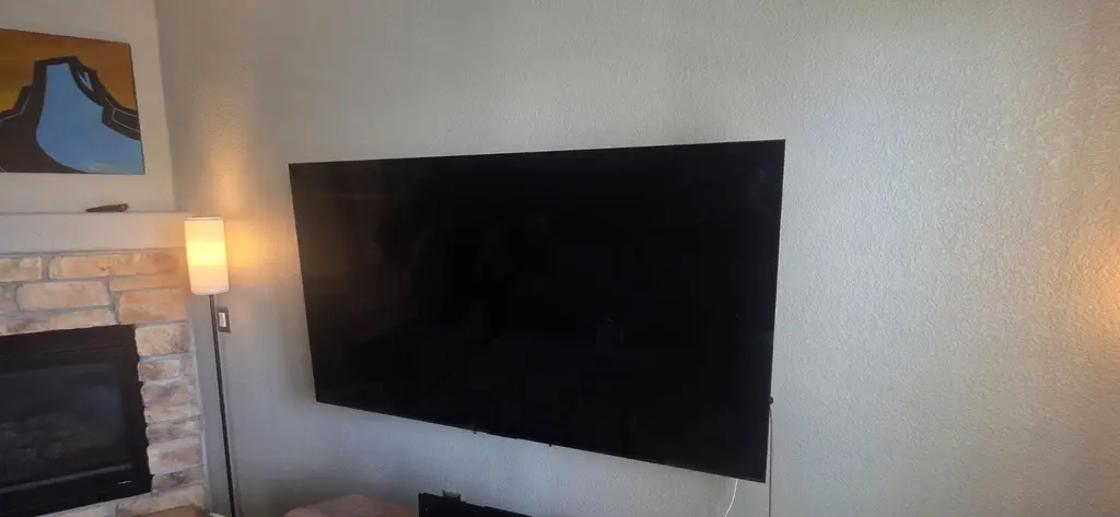 Large TV wall mounted beside a stone fireplace in Boulder