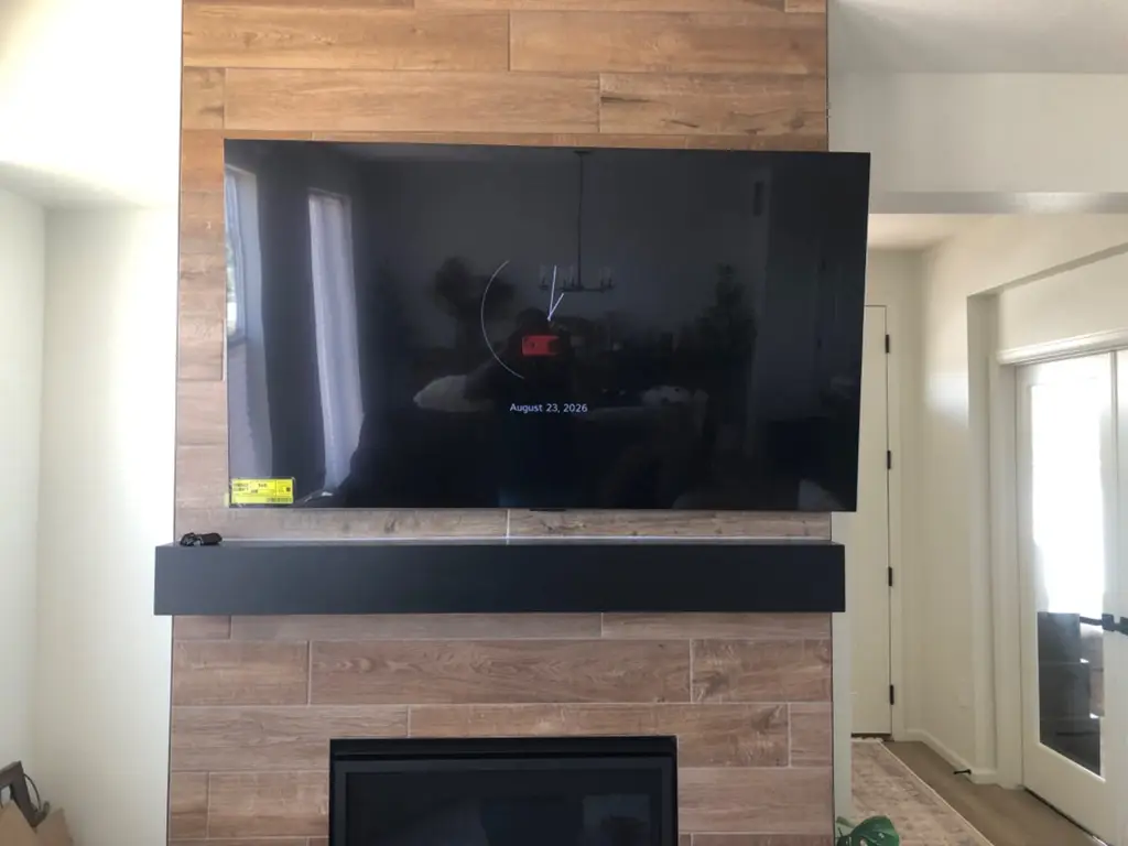TV mounted above a floating shelf and soundbar on a wood tile fireplace in Golden